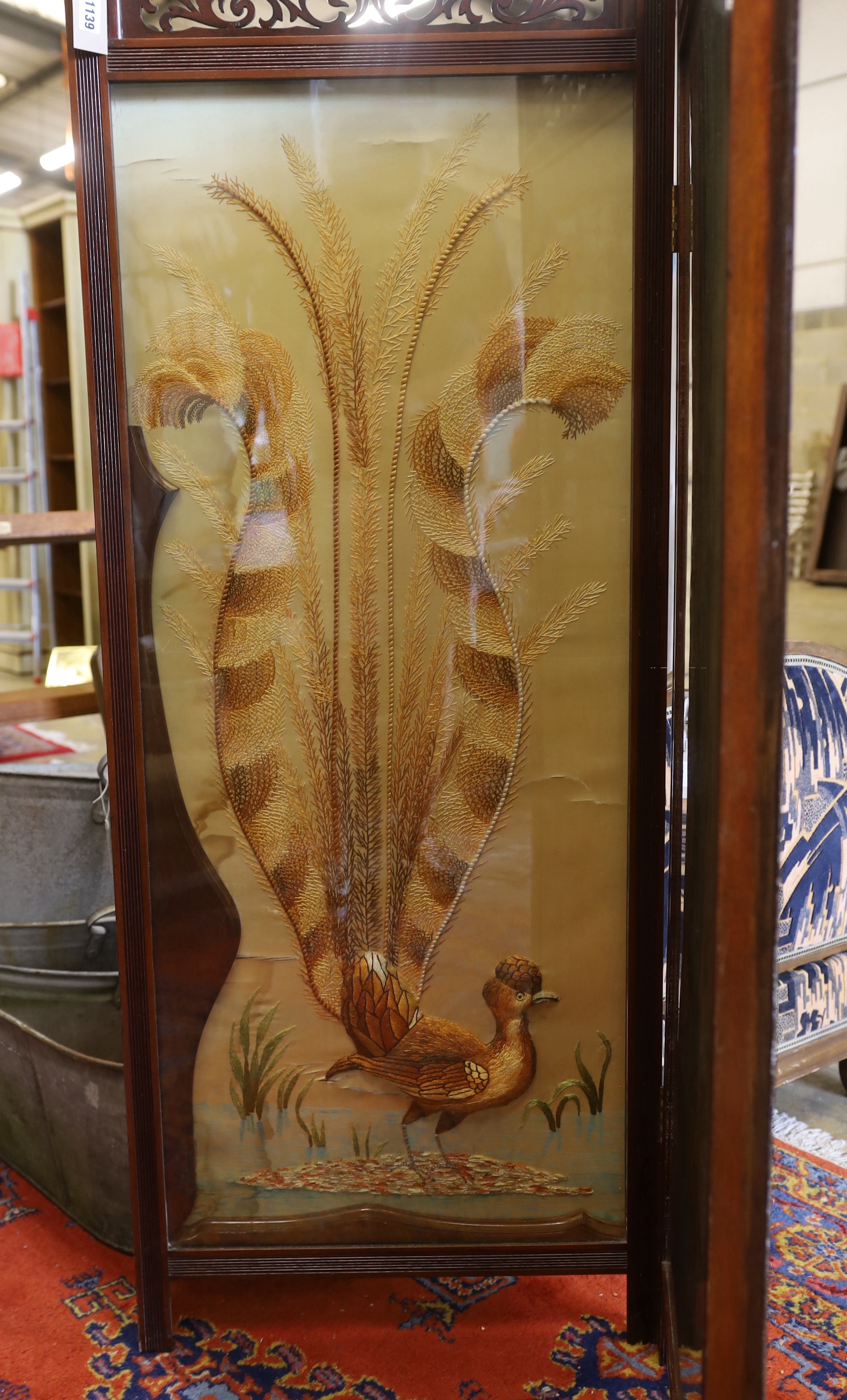 An Edwardian silk thread embroidered two fold dressing screen worked with a peacock and a stag, each panel width 57cm, height 152cm